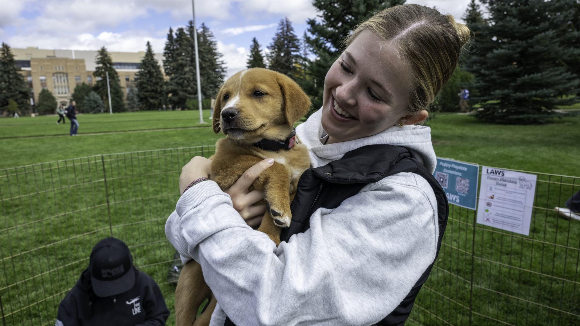A LAWS volunteer holding a puppy at a campus event